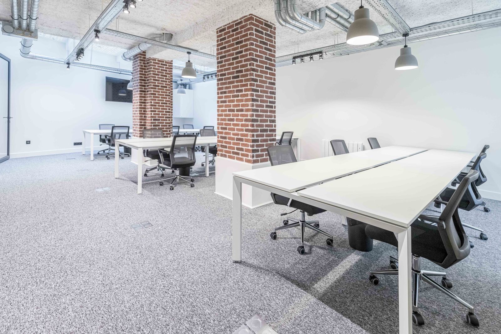 Open-space avec piliers en brique et postes en bench
